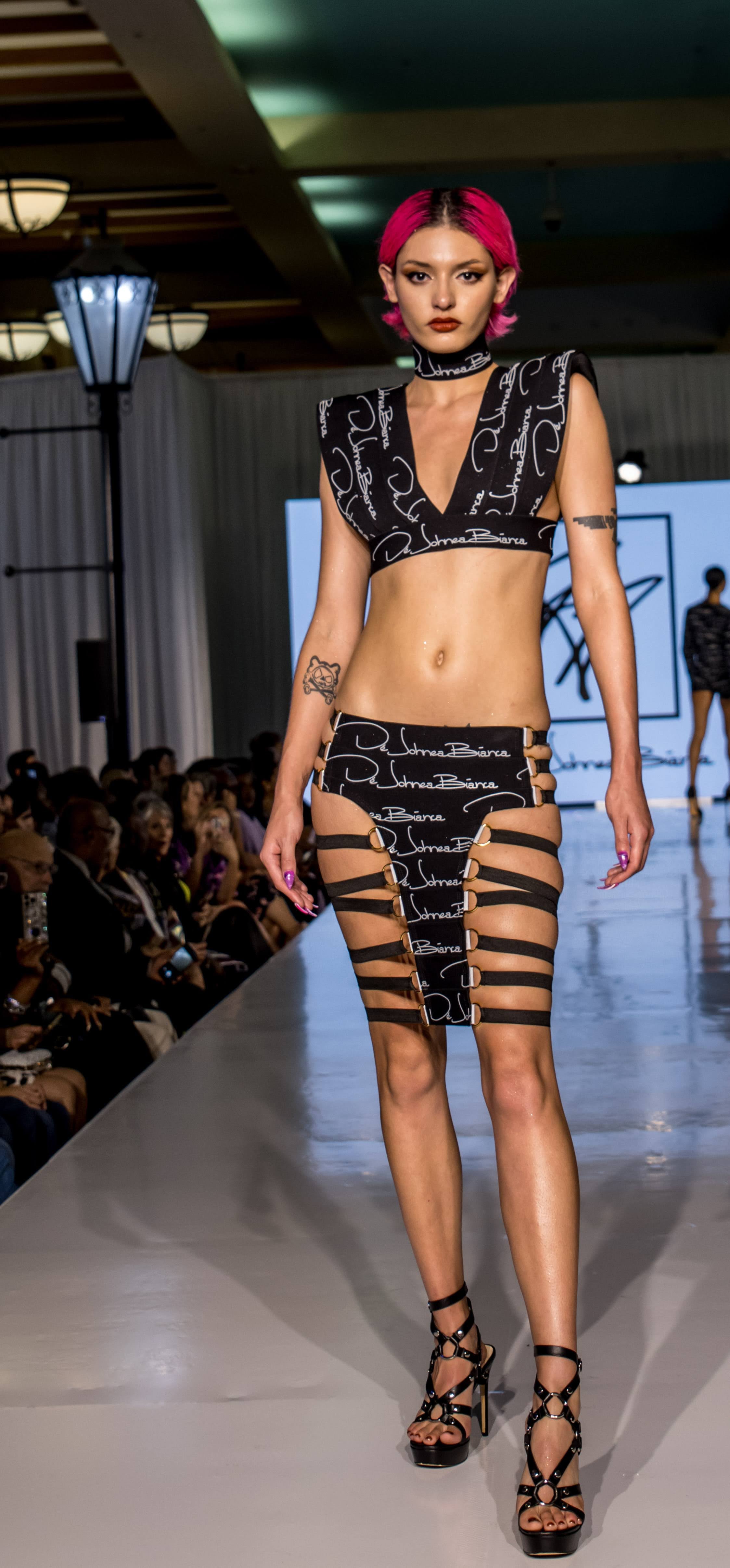 Model walking on a runway wearing a black and white outfit with 'Ernest Garcia' branding.